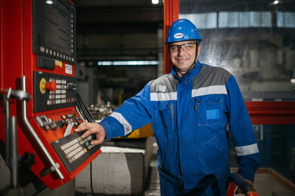 Man in safety gear works at CNC machine in a Russian factory.