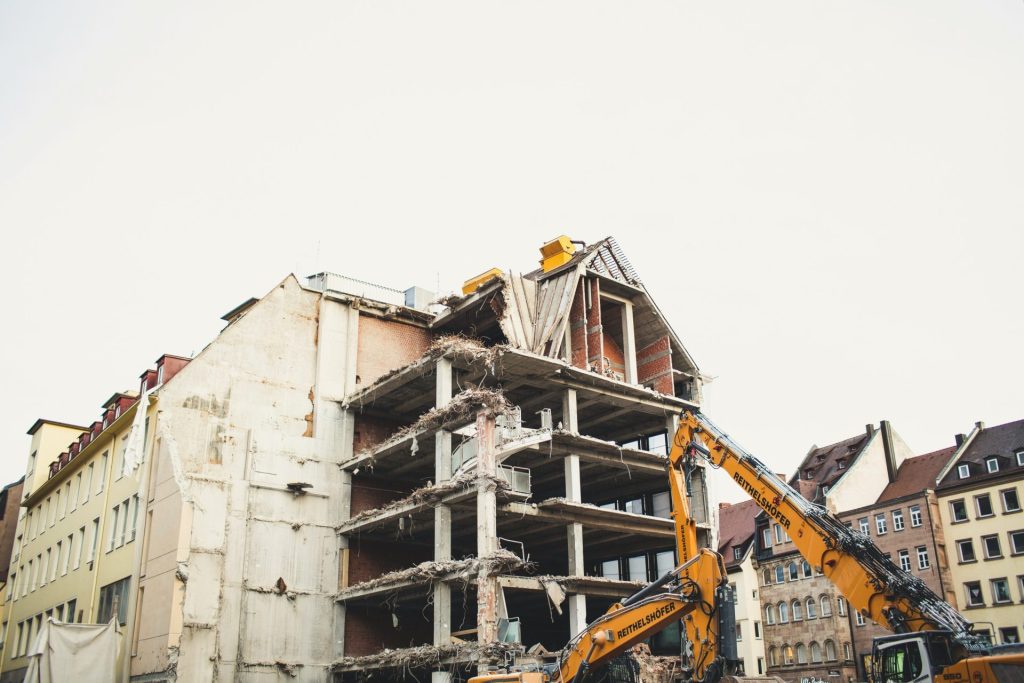 Ein Kran rammt ein mehrstöckiges Gebäude aus weißem Beton.